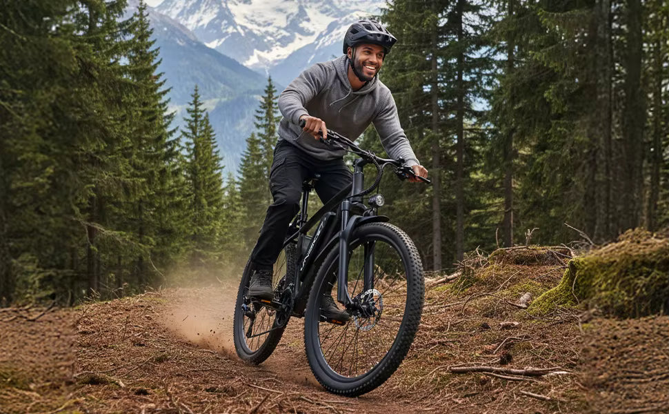 Dynamic action photograph of a cyclist riding the e-bike on a dirt path through a wooded forest