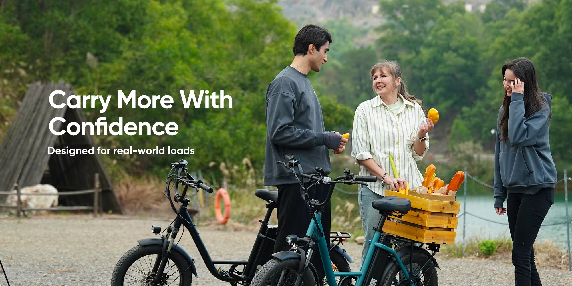 Two people with electric bikes and a third person with a crate of vegetables, with text 'Carry More With Confidence'.