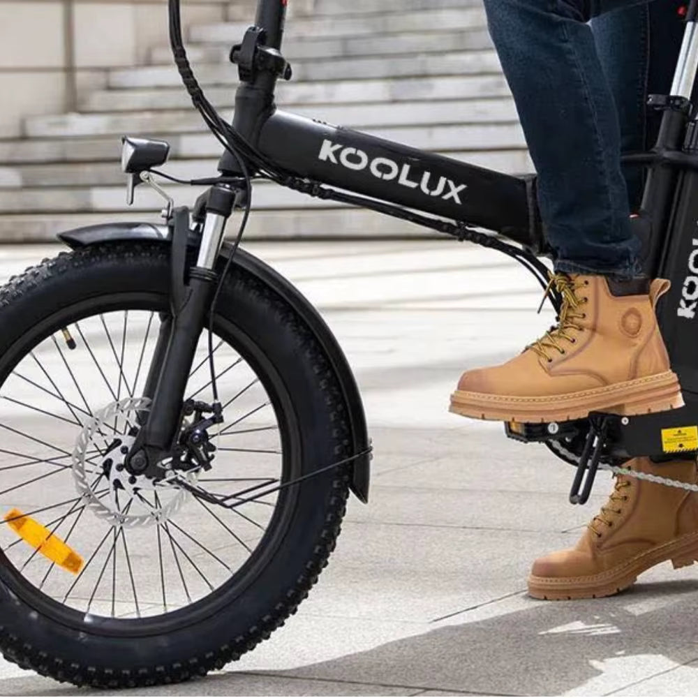 Person riding a KOOLUX X11S  electric bike on a sidewalk.