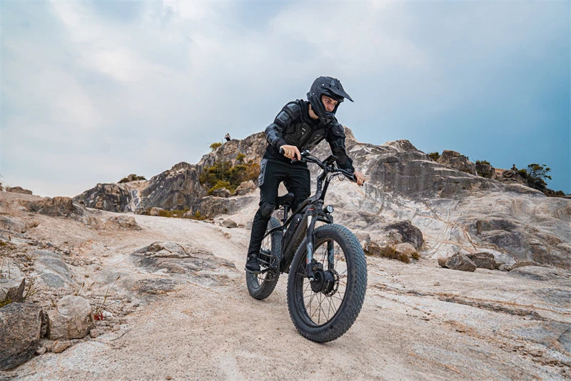 person riding an electric bike with full protective gear on. person is riding in a rocky mountainous area