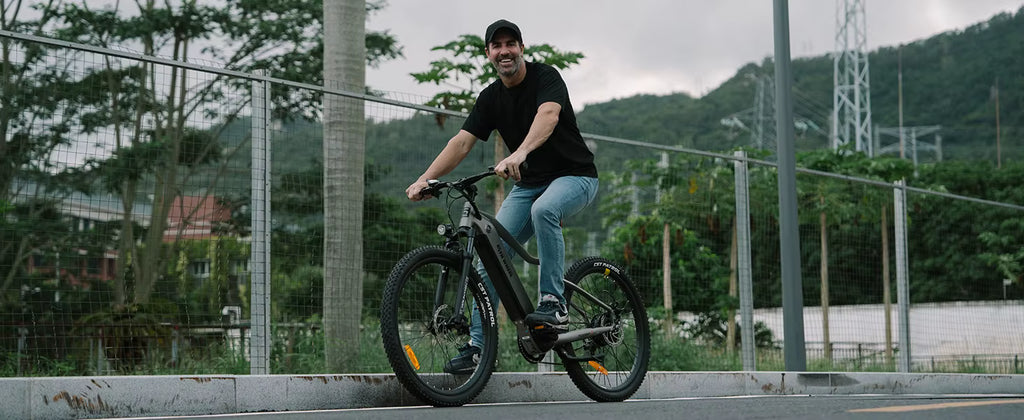 Man riding an electric bicycle on a road with trees and power lines in the background