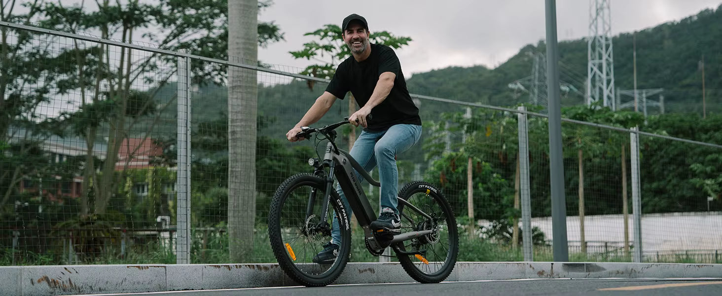 Man riding an electric bicycle on a road with trees and power lines in the background