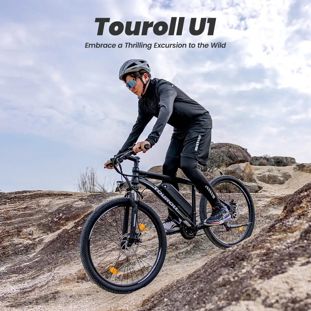 Person riding a Touroll U1 electric bike on rocky terrain with a scenic background.