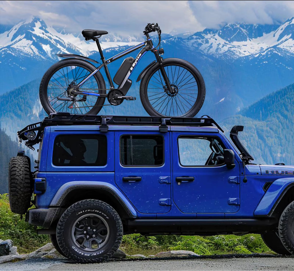 Blue Jeep with an electric bicycle on its roof against a mountainous background