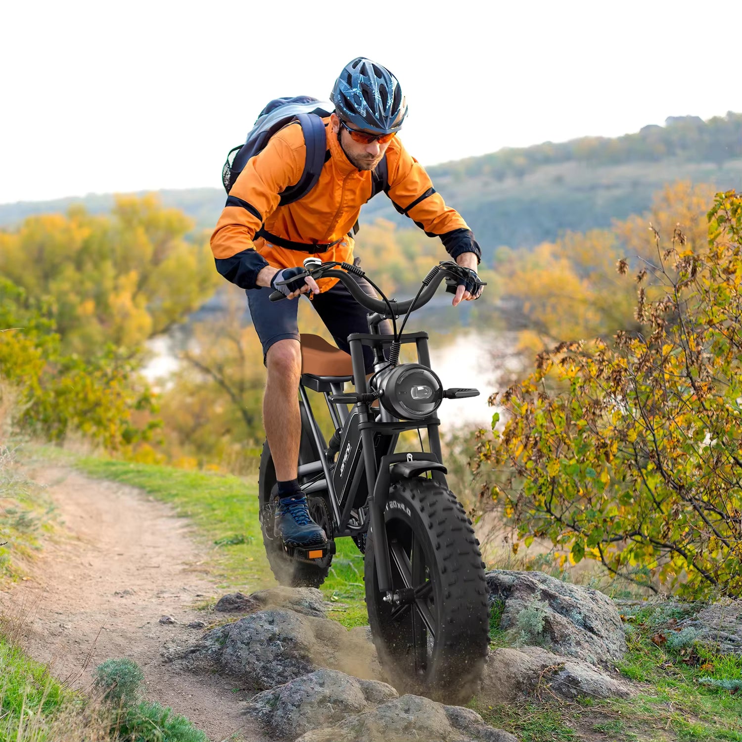 Person riding a JANSNO X50 electric mountain bike on a trail with autumn foliage in the background