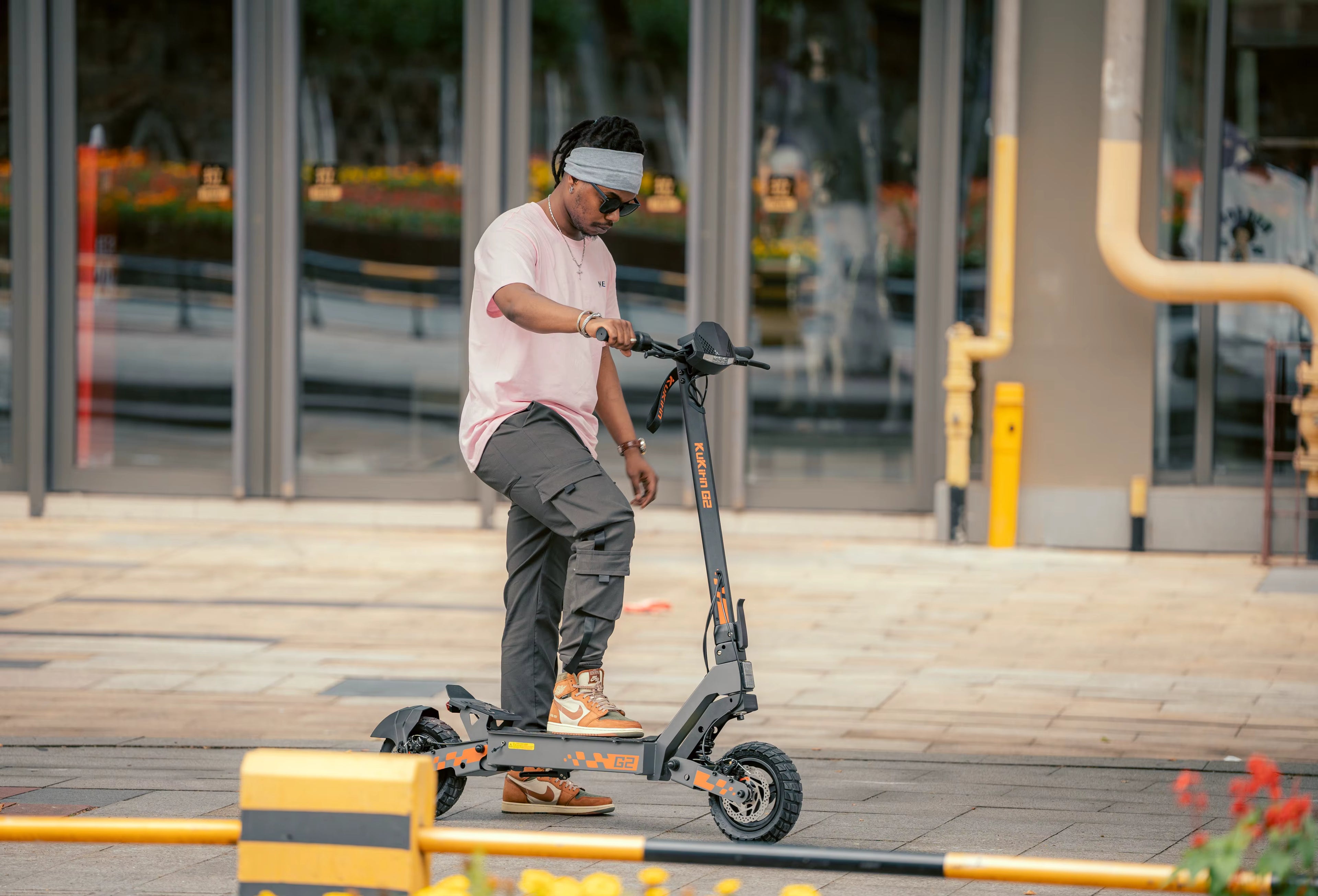 Person riding an electric scooter on a sidewalk with a building in the background