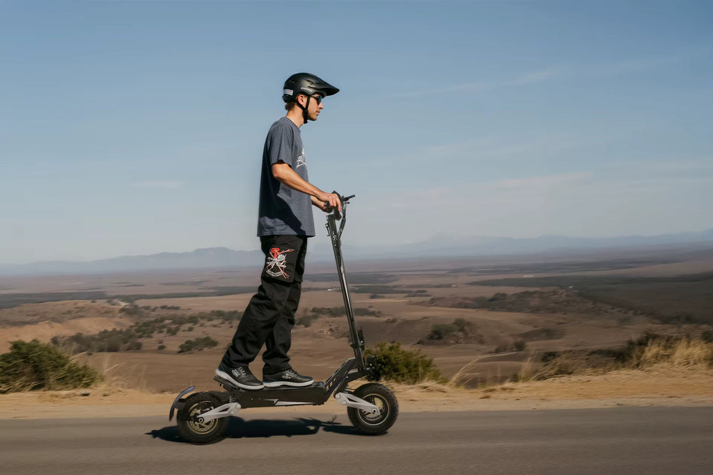 Person riding an e-scooter on a road with a scenic landscape in the background