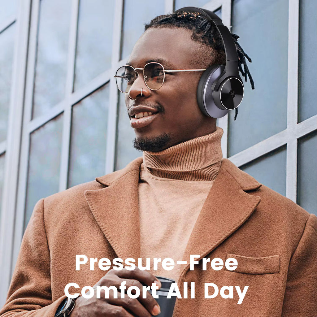 Man wearing OneOdio A10 Hybrid ANC Over-Ear Bluetooth headphones with text 'Pressure-Free Comfort All Day' against a windowed building background