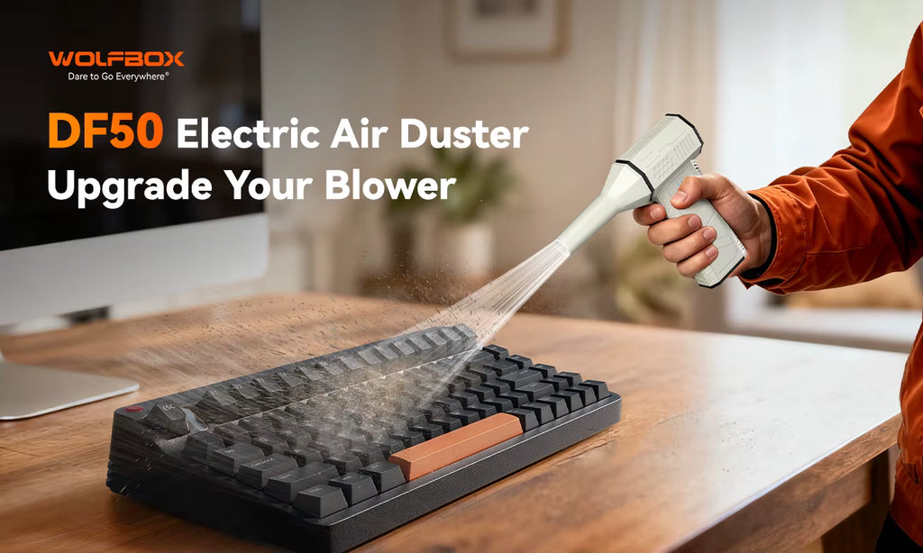 WOLFBOX DF50 Electric Air Duster being used to blow dust off a computer keyboard on a wooden desk
