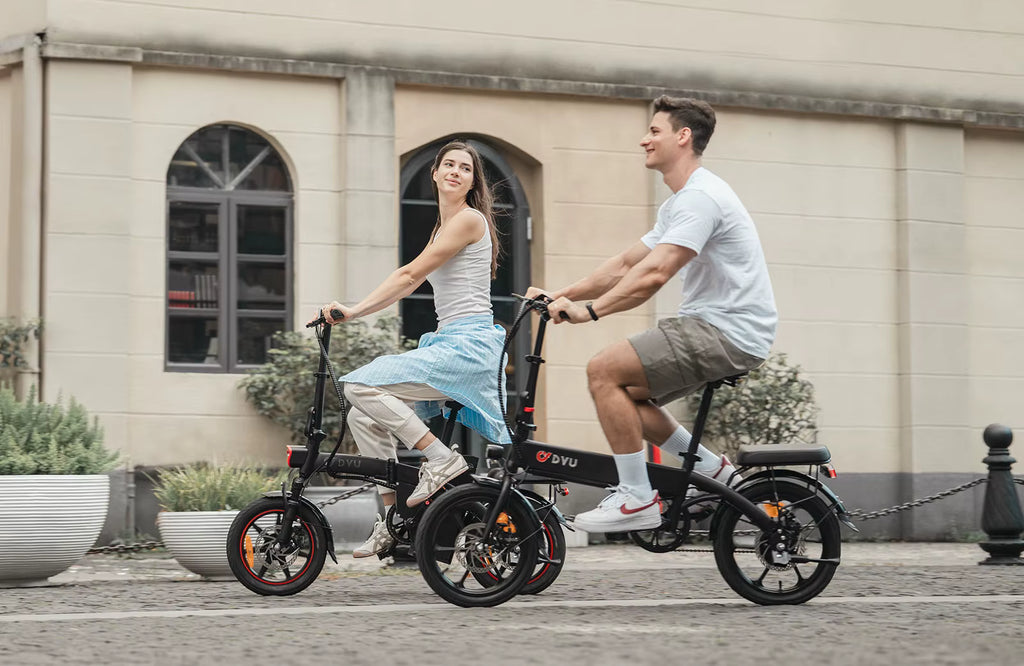 Two people riding DYU A1F Pro Folding E-Bike  electric bikes on a street with a building in the background