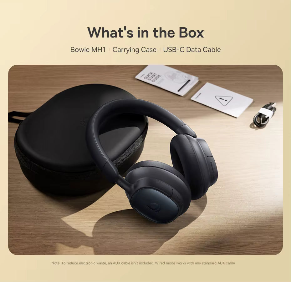 Baseus Bowie MH1 headphones displayed on a wooden surface beside a black carrying case, USB‑C data cable, and instruction manuals, with the heading “What’s in the Box,” showing included accessories and a note about AUX cable compatibility for wired mode.