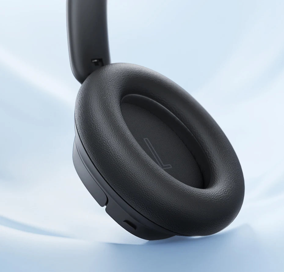 Black headphones with soft ear pads on a light blue background