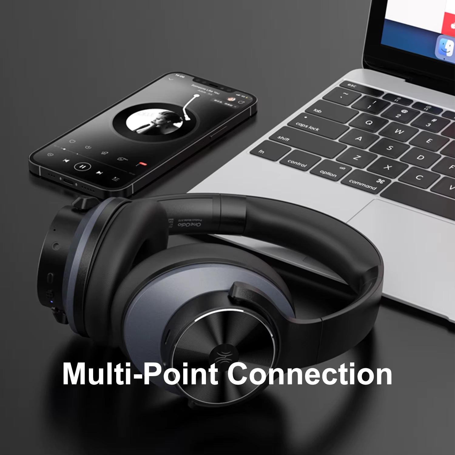 OneOdio A10 Hybrid ANC Over-Ear Bluetooth Headphones with smartphone and laptop on a dark surface, highlighting multi-point connection feature.