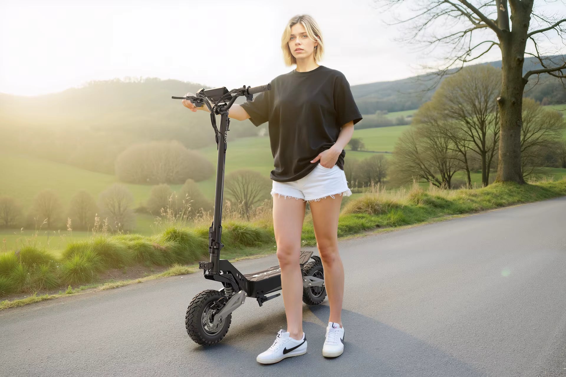 Person standing on a road with an electric scooter in a scenic outdoor setting