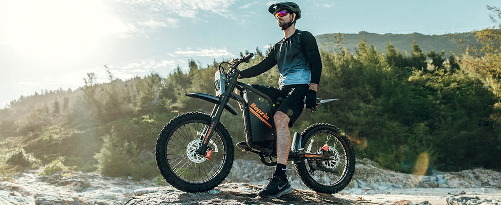 person standing in a mountainous area on a sunny day with an electric bike