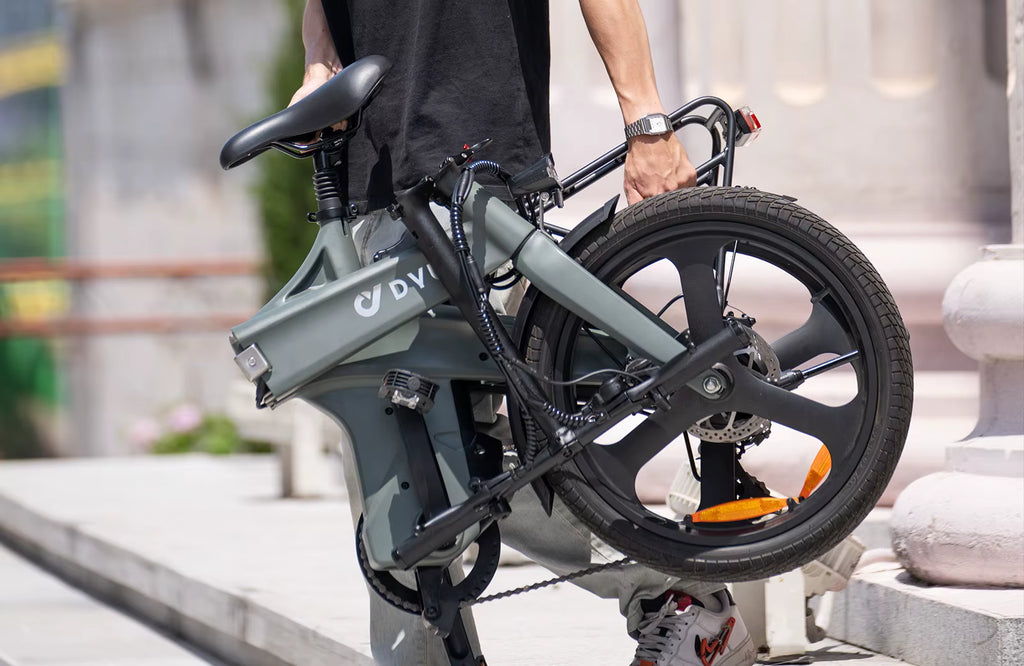 Person holding a folded electric bike with 'DVI' branding on a blurred background