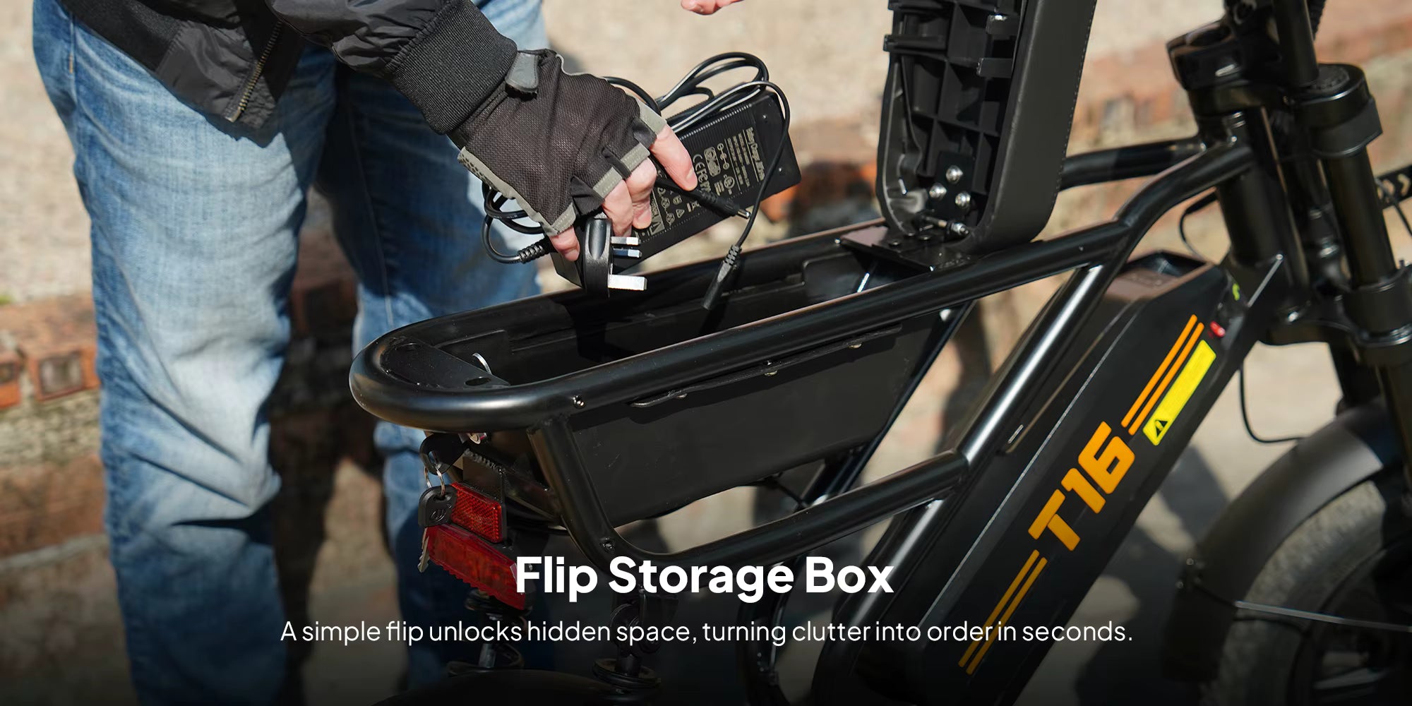 Person using a power adapter on an e-bike with a flip storage box labeled 'T16'.