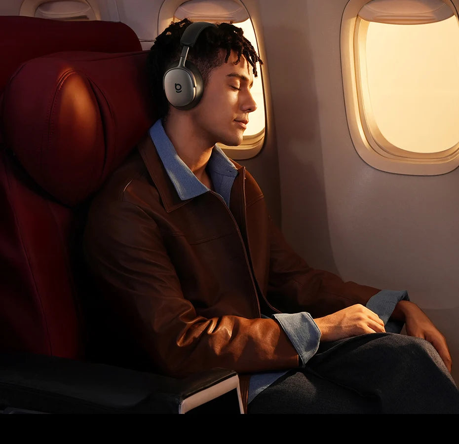 Man wearing Baseus Inspire XH1 headphones on an airplane, looking out the window.