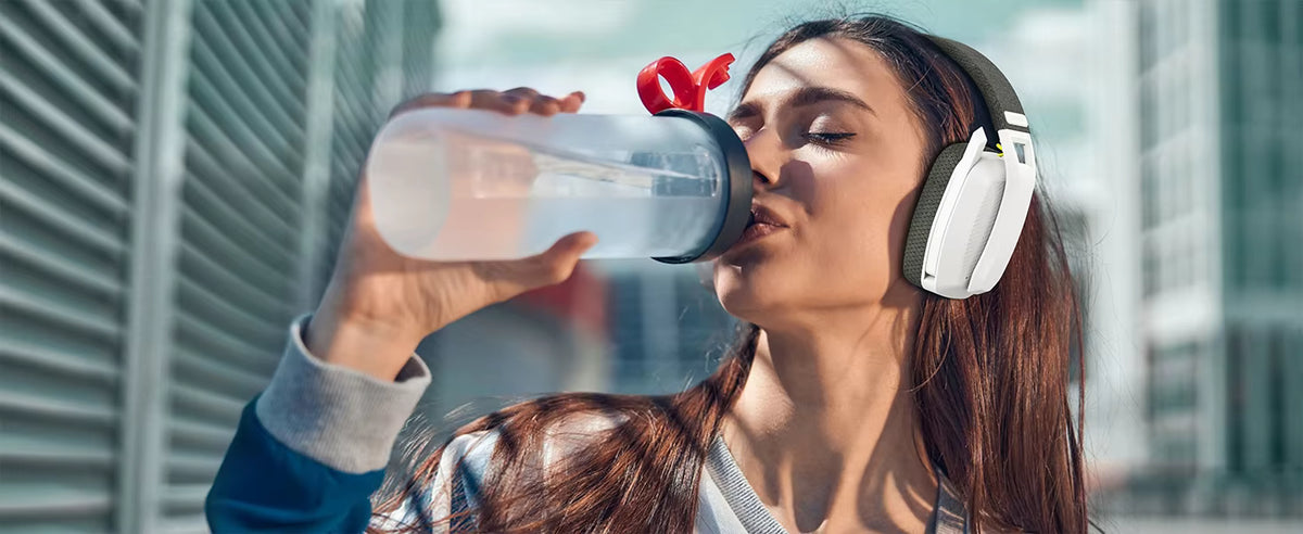 Lifestyle photograph of a person wearing the white headset while drinking water after a workout