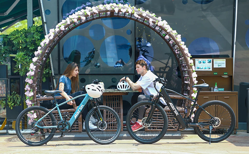 Two people sitting relaxing with bicycles in front of a decorative archway with flowers.
