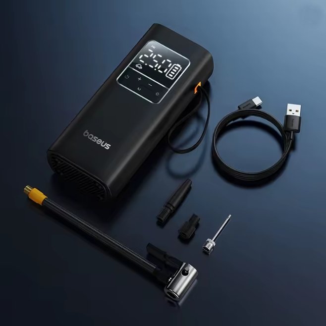 A black portable air pump with a digital display screen, shown with its accessories including a USB charging cable, a hose with a yellow connector, and various nozzles on a dark blue background. The brand name 'baseus' is visible on the pump.