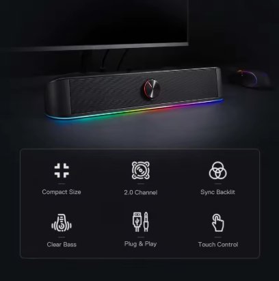 A compact black computer speaker bar with RGB rainbow lighting along the bottom edge, shown in front of a monitor and mouse on a dark desk. A feature summary panel below lists compact size, 2 channel, clear bass