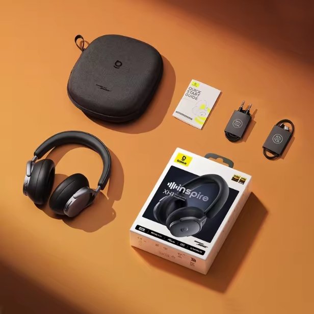 A pair of black over-ear Baseus Inspire XH1 headphones with a matching hard carrying case, shown with the retail box, a small card, and two small accessories on an orange surface.