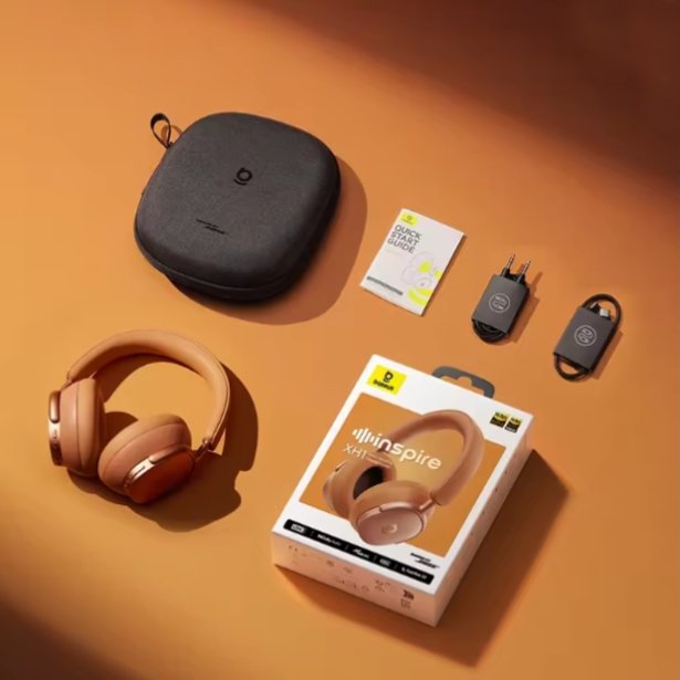 A pair of Sunset Coral over-ear Baseus Inspire XH1 headphones with a matching hard carrying case, shown with the retail box, a small card, and two small accessories on an orange surface.