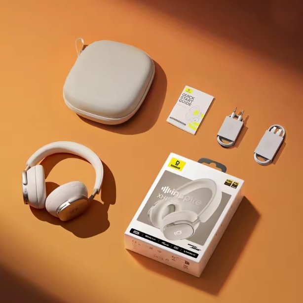 A pair of Starlight Off-White over-ear Baseus Inspire XH1 headphones with a matching hard carrying case, shown with the retail box, a small card, and two small accessories on an orange surface.