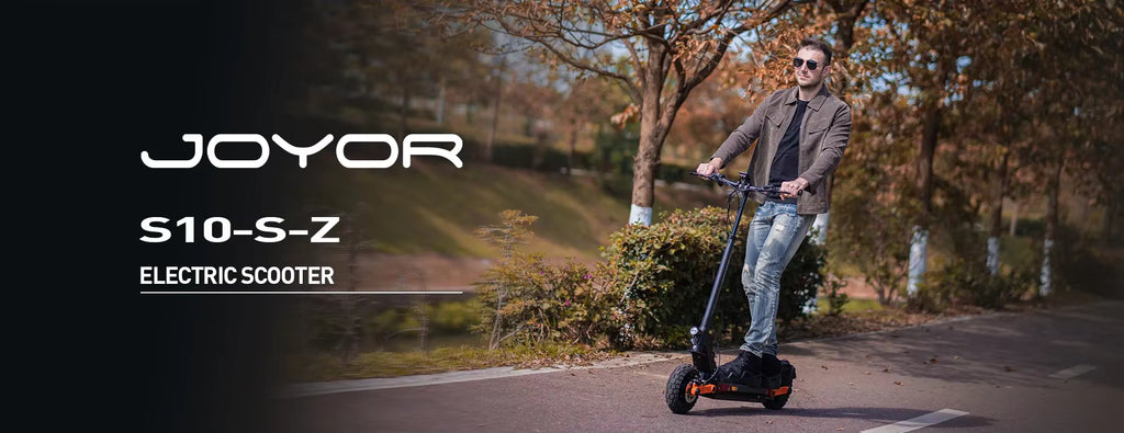 Man riding a Joyor S10-S-Z electric scooter on a path with trees and grass in the background