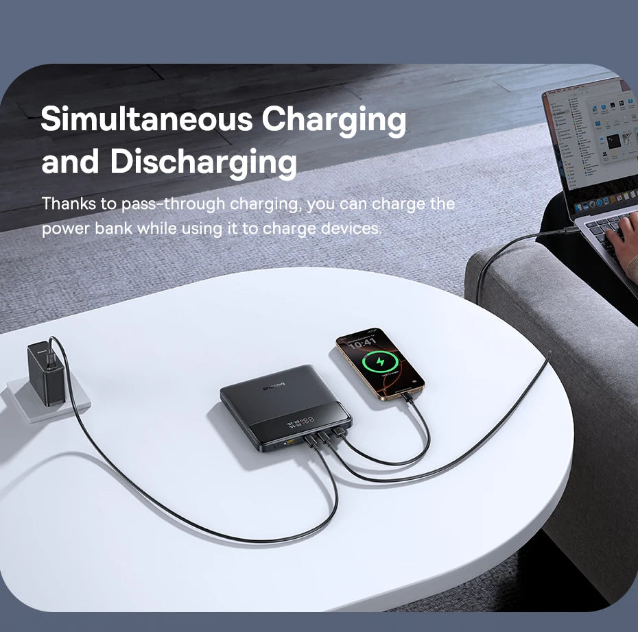 Power bank charging a smartphone and tablet on a white table with text about simultaneous charging and discharging.