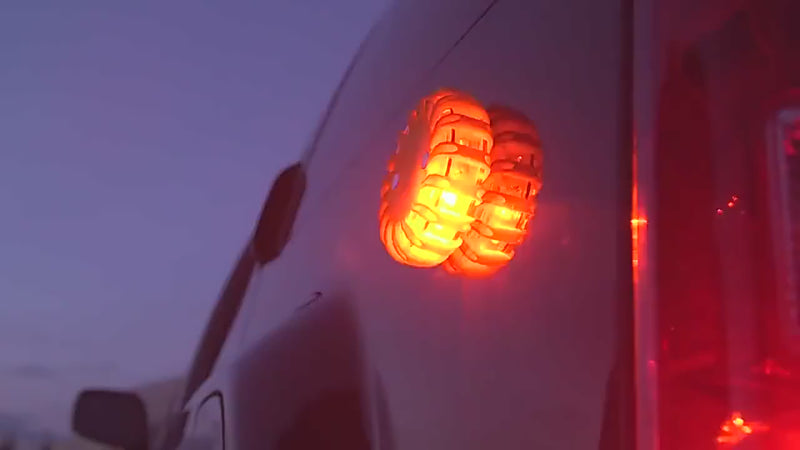 High-visibility magnetic LED emergency road flare flashing on the rear of a vehicle during a dark night-time roadside hazard scenario