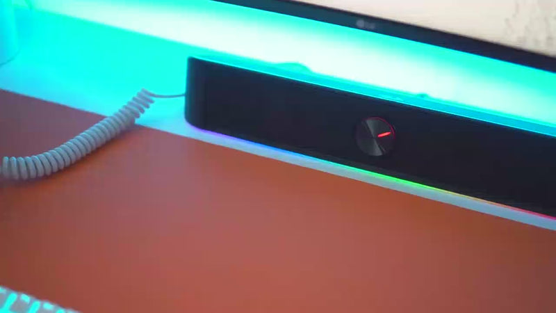 Redragon GS560 Adiemus RGB desktop soundbar showing dynamic lighting effects under a monitor with close up shots of the volume knob and USB powered setup demonstrating stereo audio performance and compact desk placement.