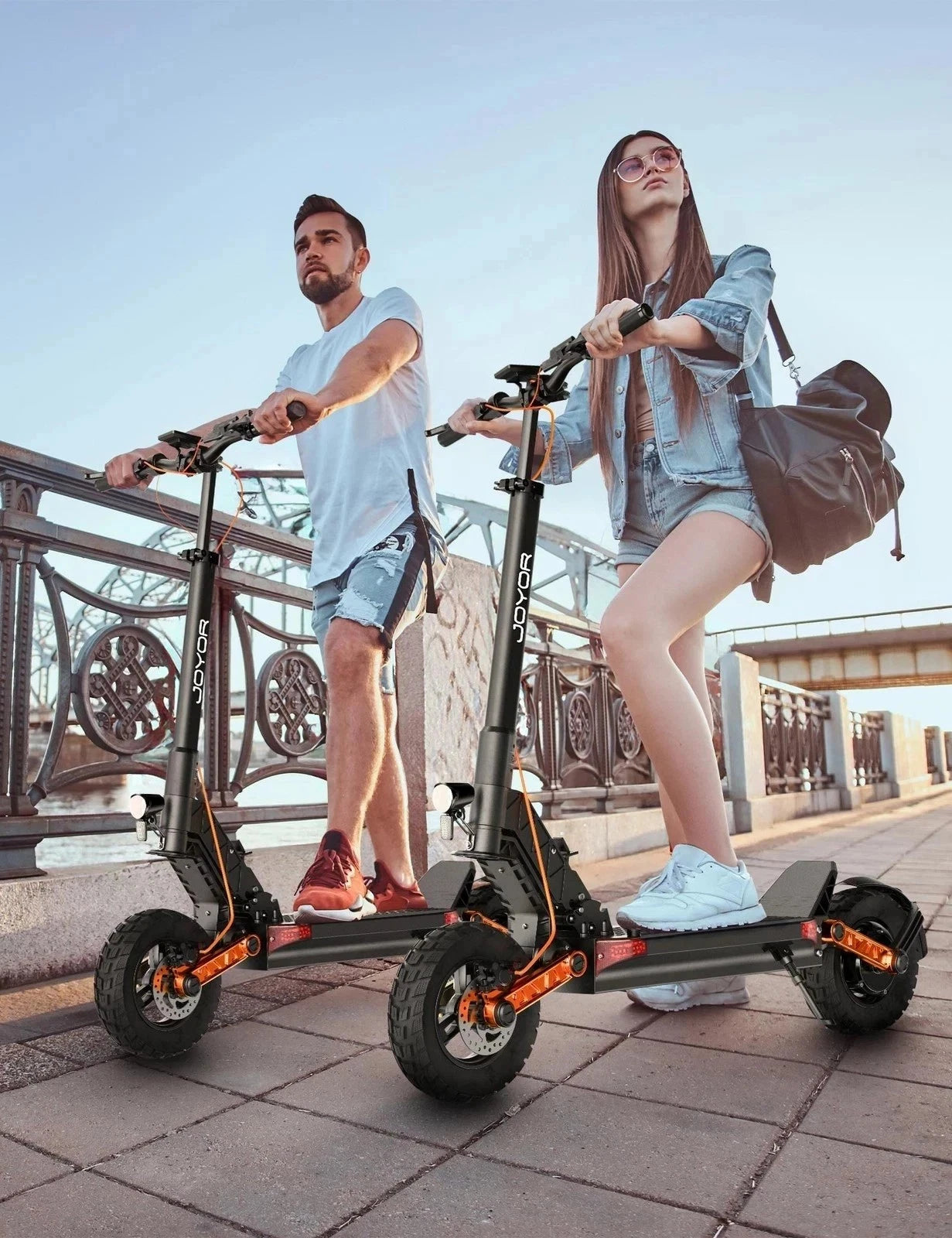 Two people riding electric scooters on a sidewalk.