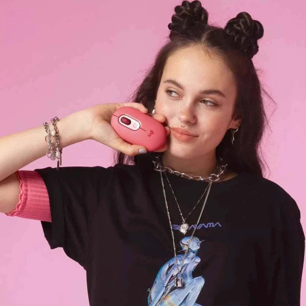 Person holding a pink mouse against a pink background
